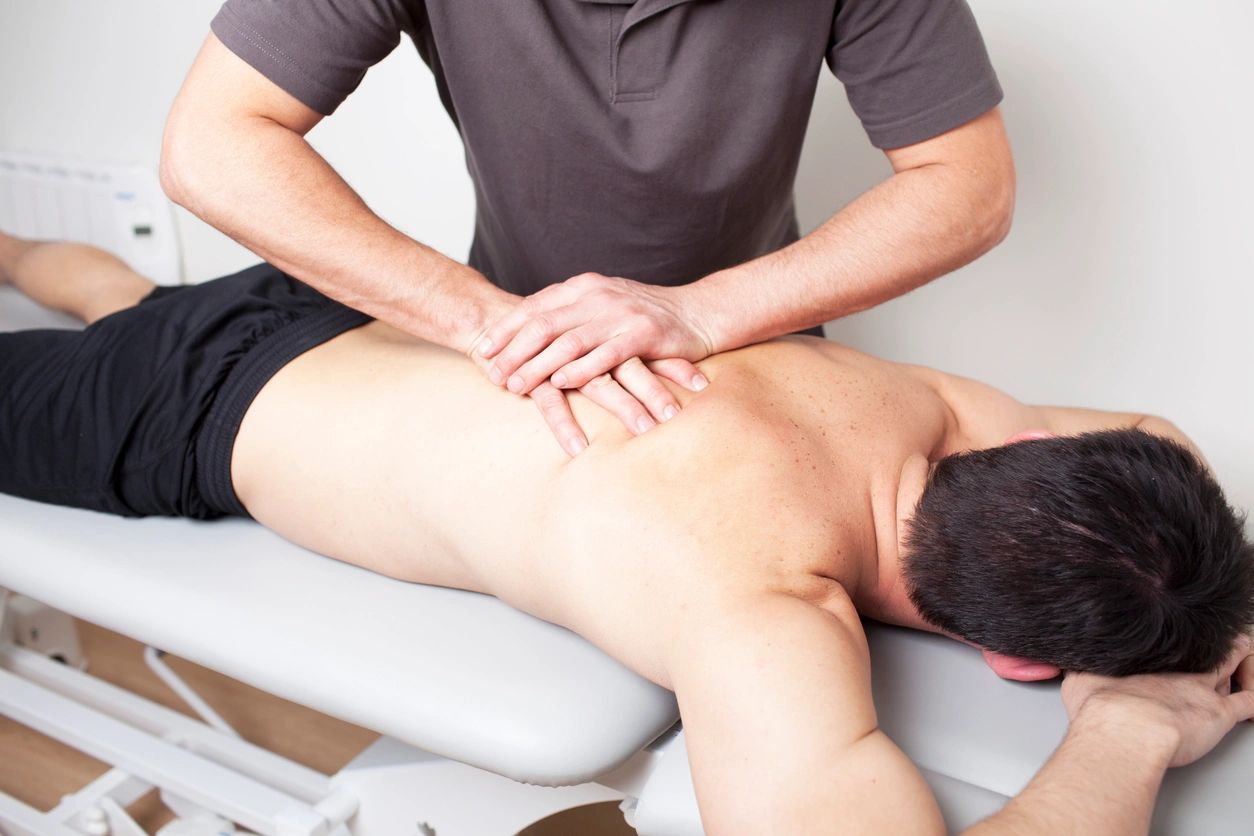 Therapist performing clinical massage therapy on a client's back.