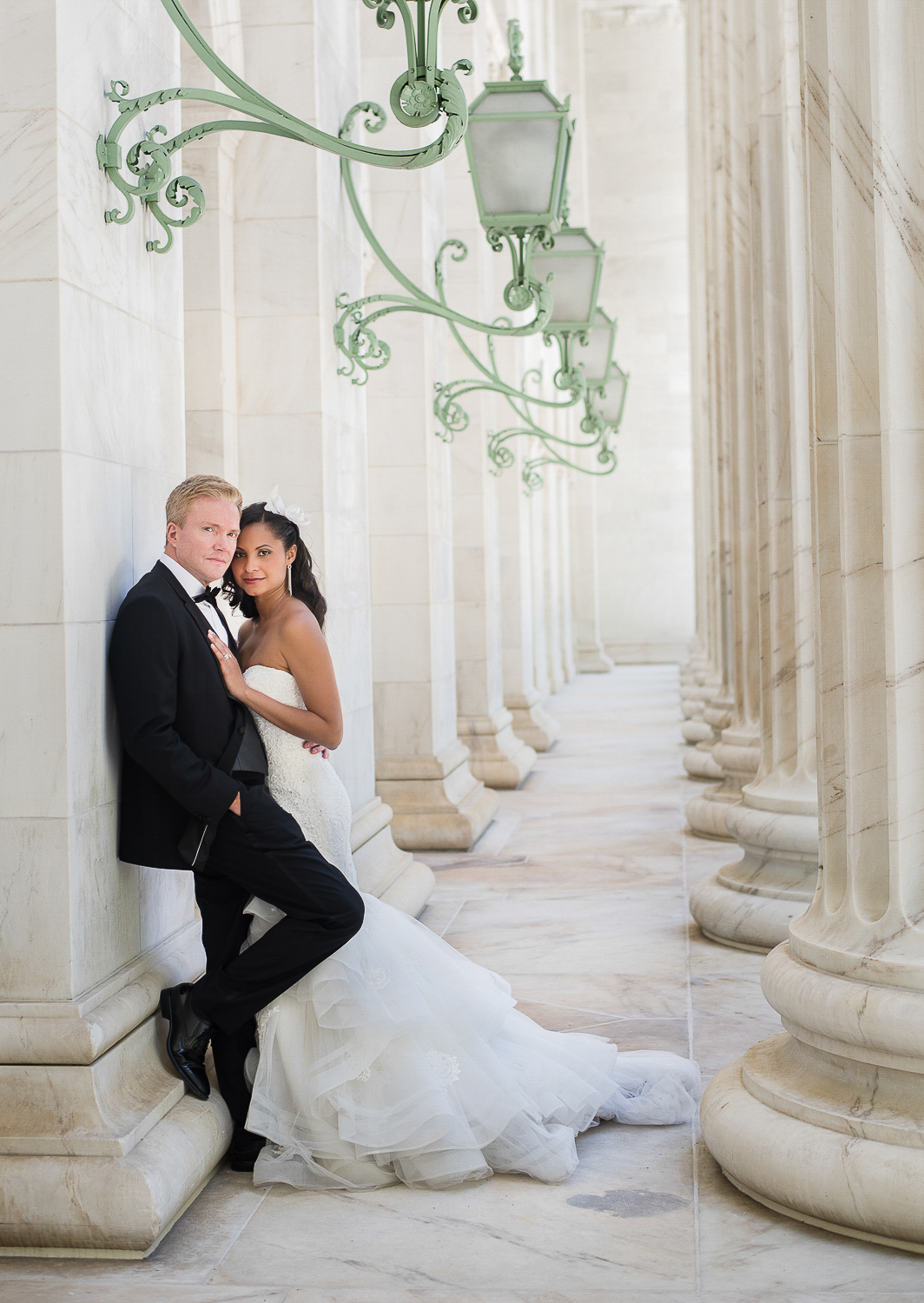 Bride and groom posing by stone pillars and lanterns.