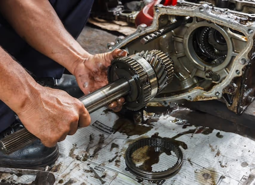 Mechanic holding transmission shaft and gears during repair.