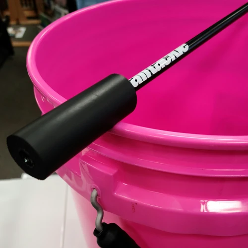 A black fishing rod resting on top of a bright pink bucket.