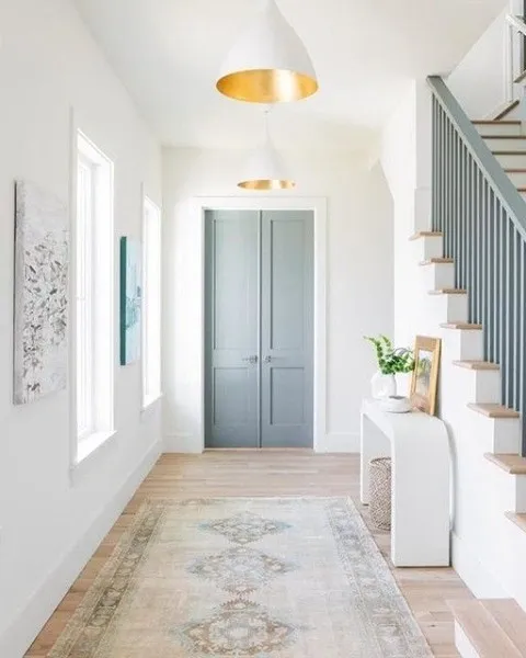 Brightly lit home entryway with freshly painted white walls and gray double doors.