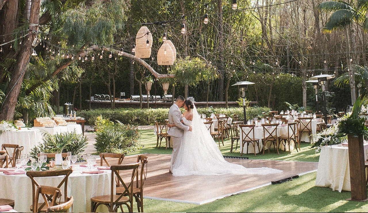 Bride and groom dancing outdoors at a lush garden wedding reception.