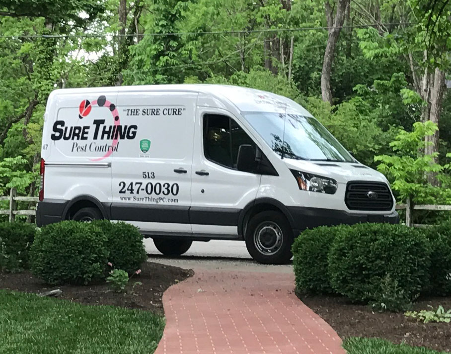 Sure Thing Pest Control white service van parked in a residential driveway.