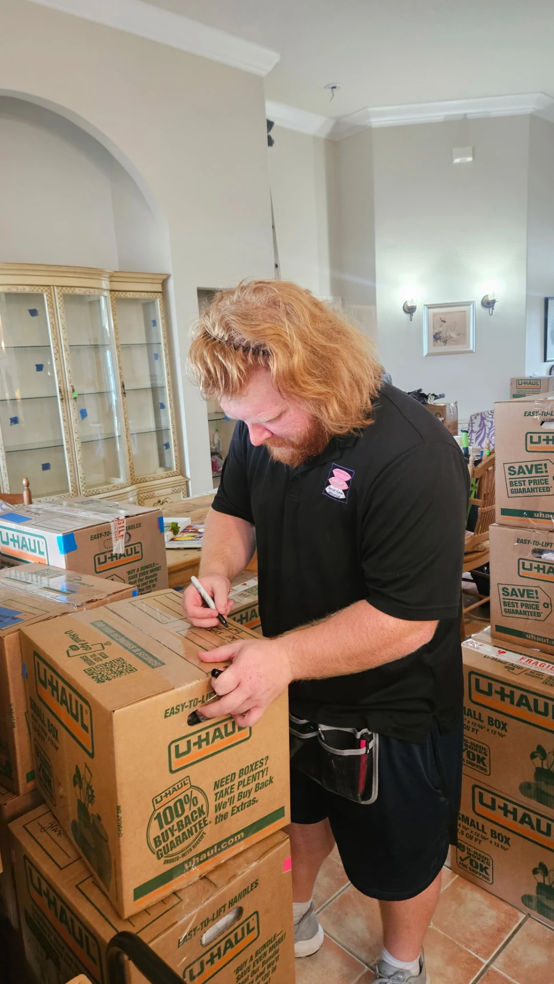 Team member labeling a cardboard moving box inside a home during a senior move.