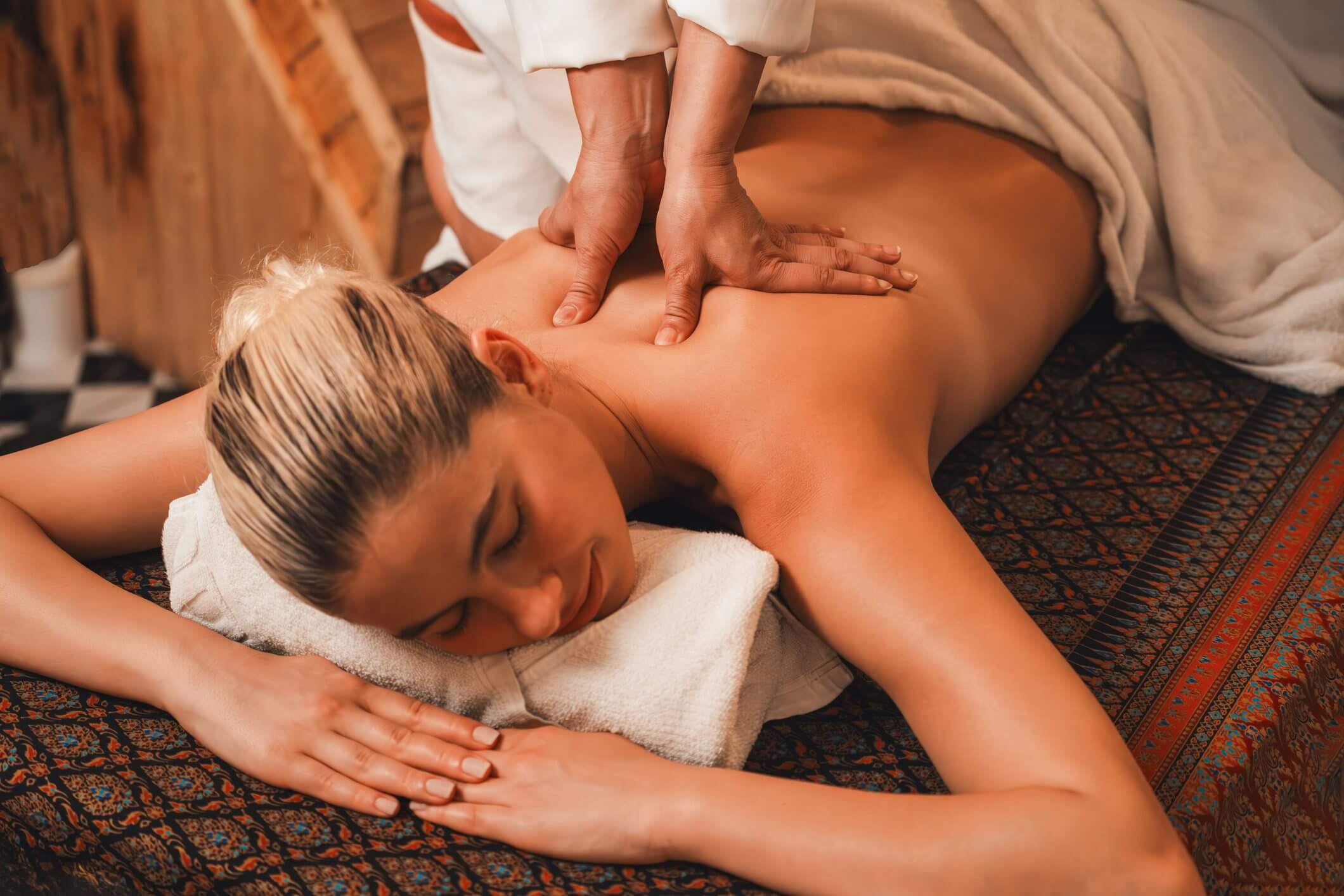 Massage therapist giving a back massage to a client lying on a treatment table.