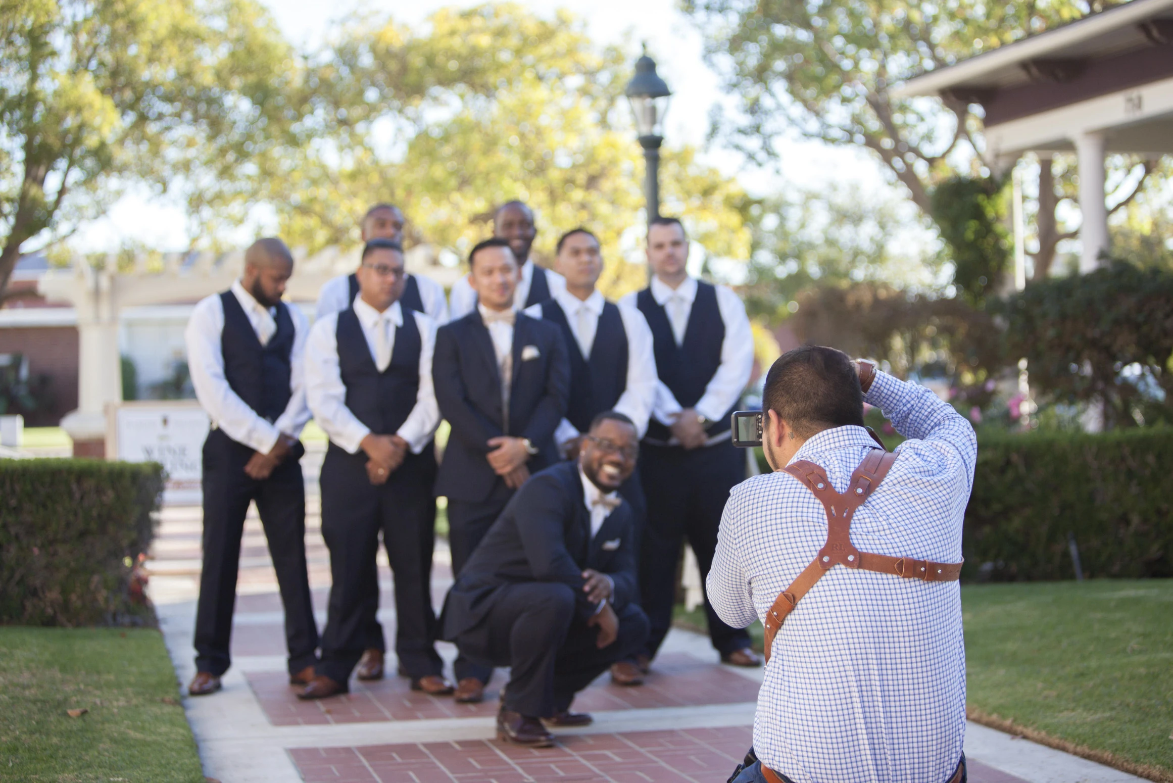 Photographer taking pictures of groomsmen outdoors on a wedding day.