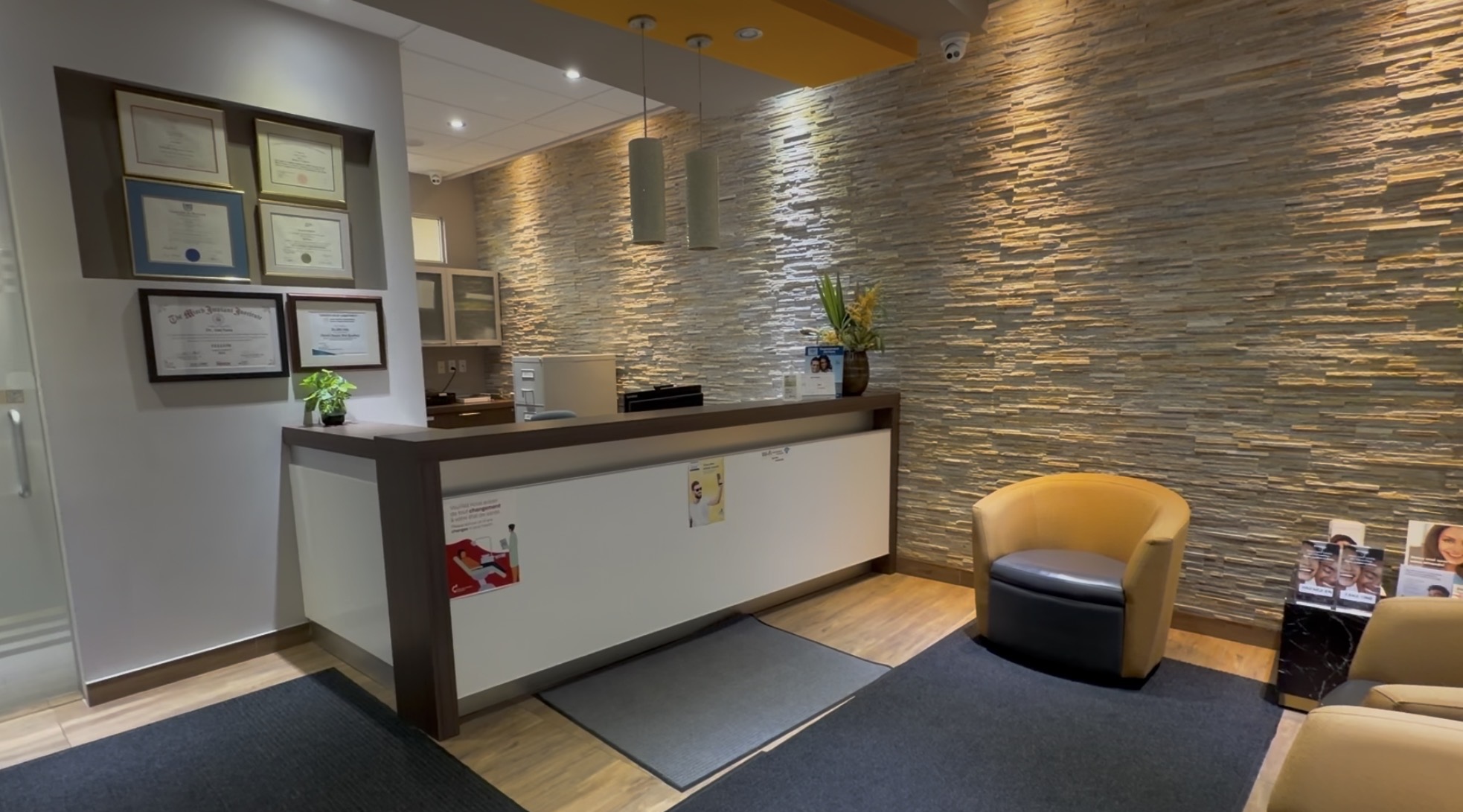 Reception desk and waiting area with stone wall at Clinique Dentaire Saba in Laval.