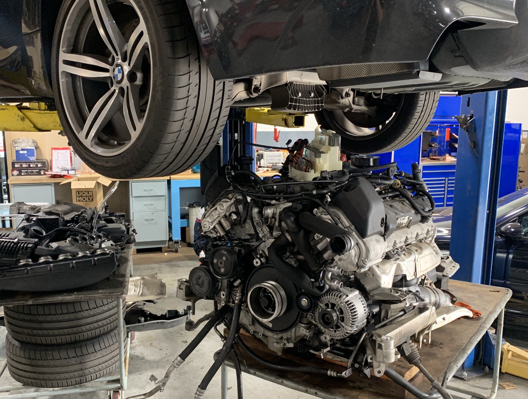 An engine removed from a BMW hoisted on a lift inside the EuroX Performance shop.