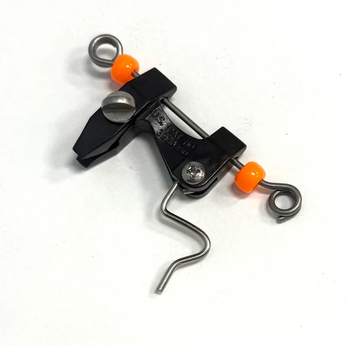 Close-up of a black and metal outrigger release clip with orange beads on a white background.