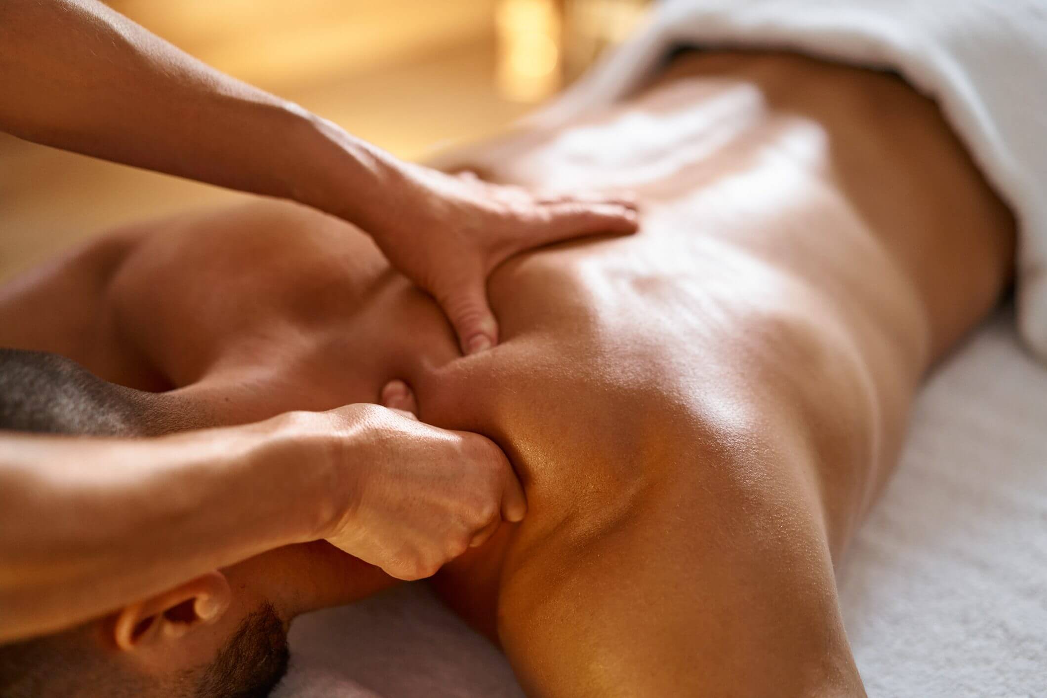 Massage therapist performing deep tissue work on a client's upper back.