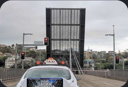 Taxi stopped at a raised bridge with red traffic lights.