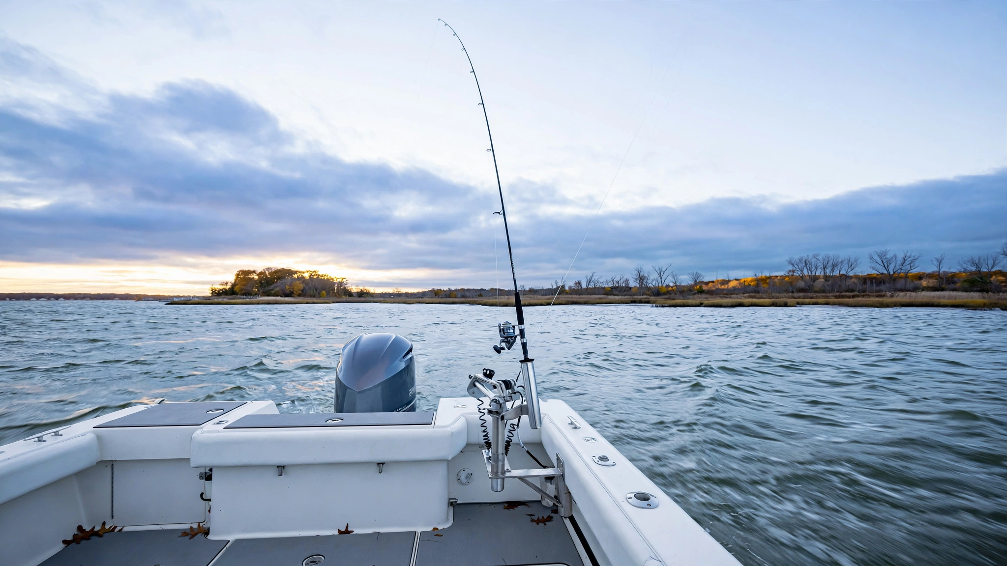 Center console boat stern in a fall breeze with a fishing kite flying over a Chesapeake Bay point and a short kite rod seated